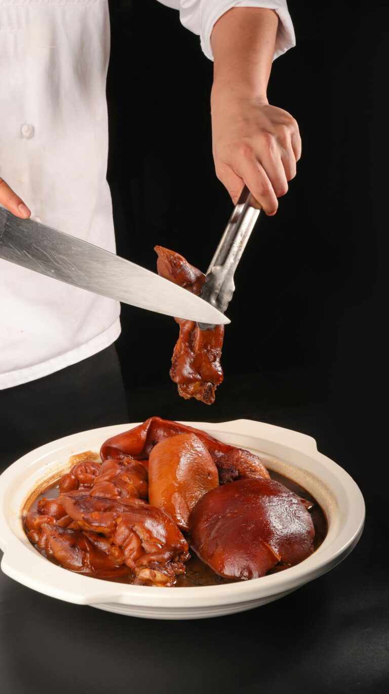 Chef slicing and serving a prepared pork dish on a black background.