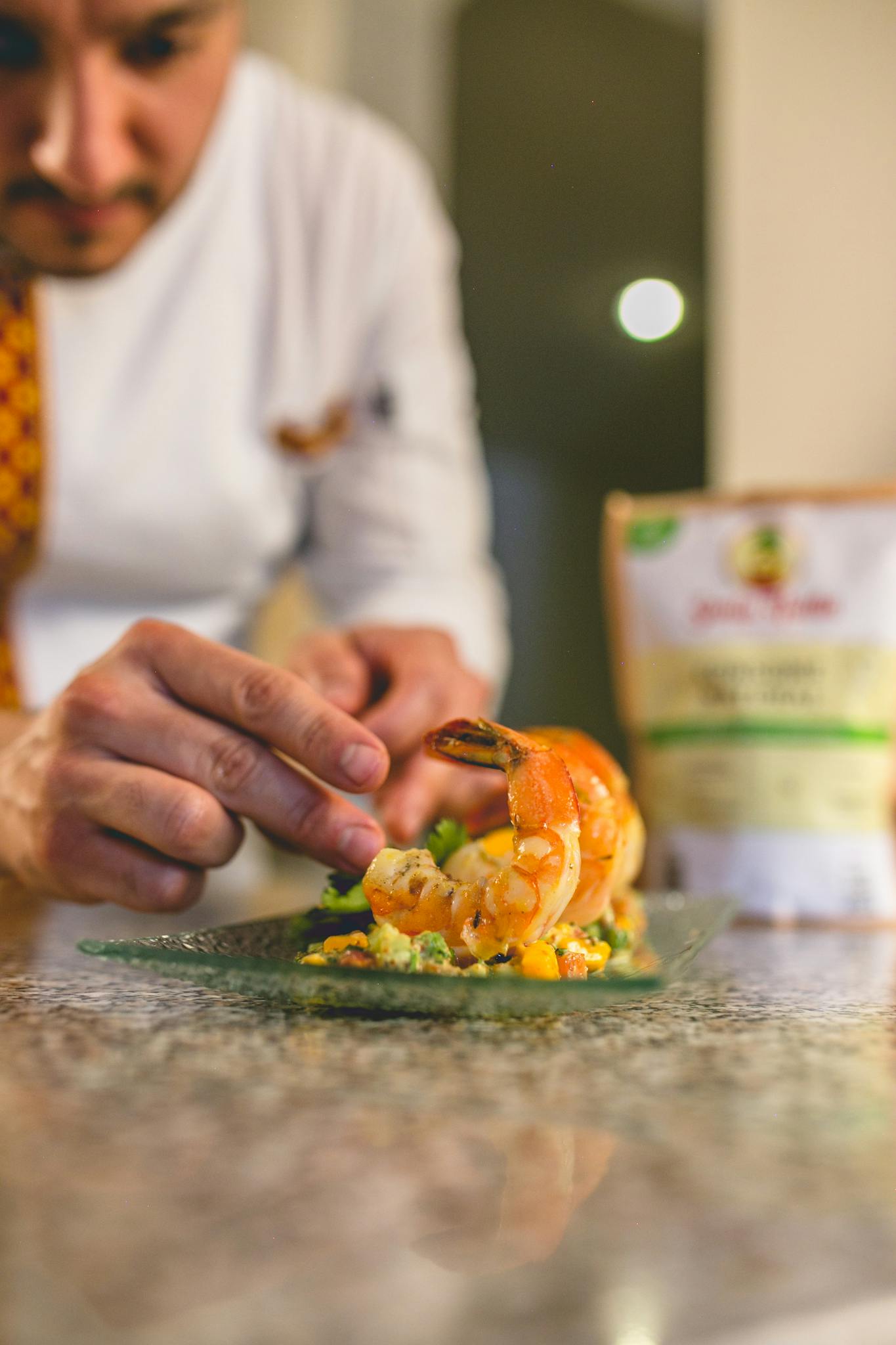 Close-up of a chef preparing a gourmet shrimp dish on a kitchen counter, showcasing culinary skills.