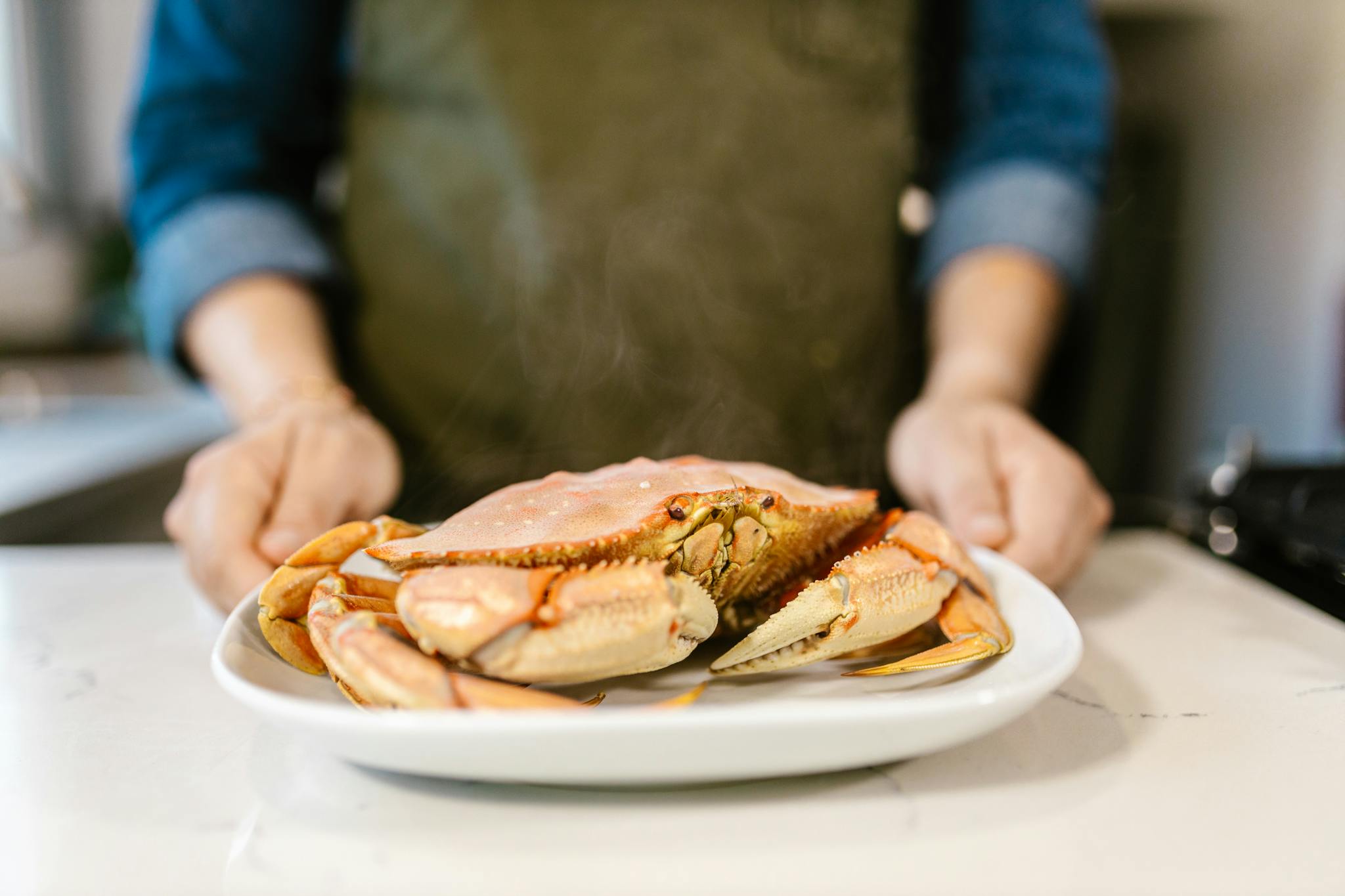Close-up of a freshly prepared crab on a plate being held by a chef, ready to serve.