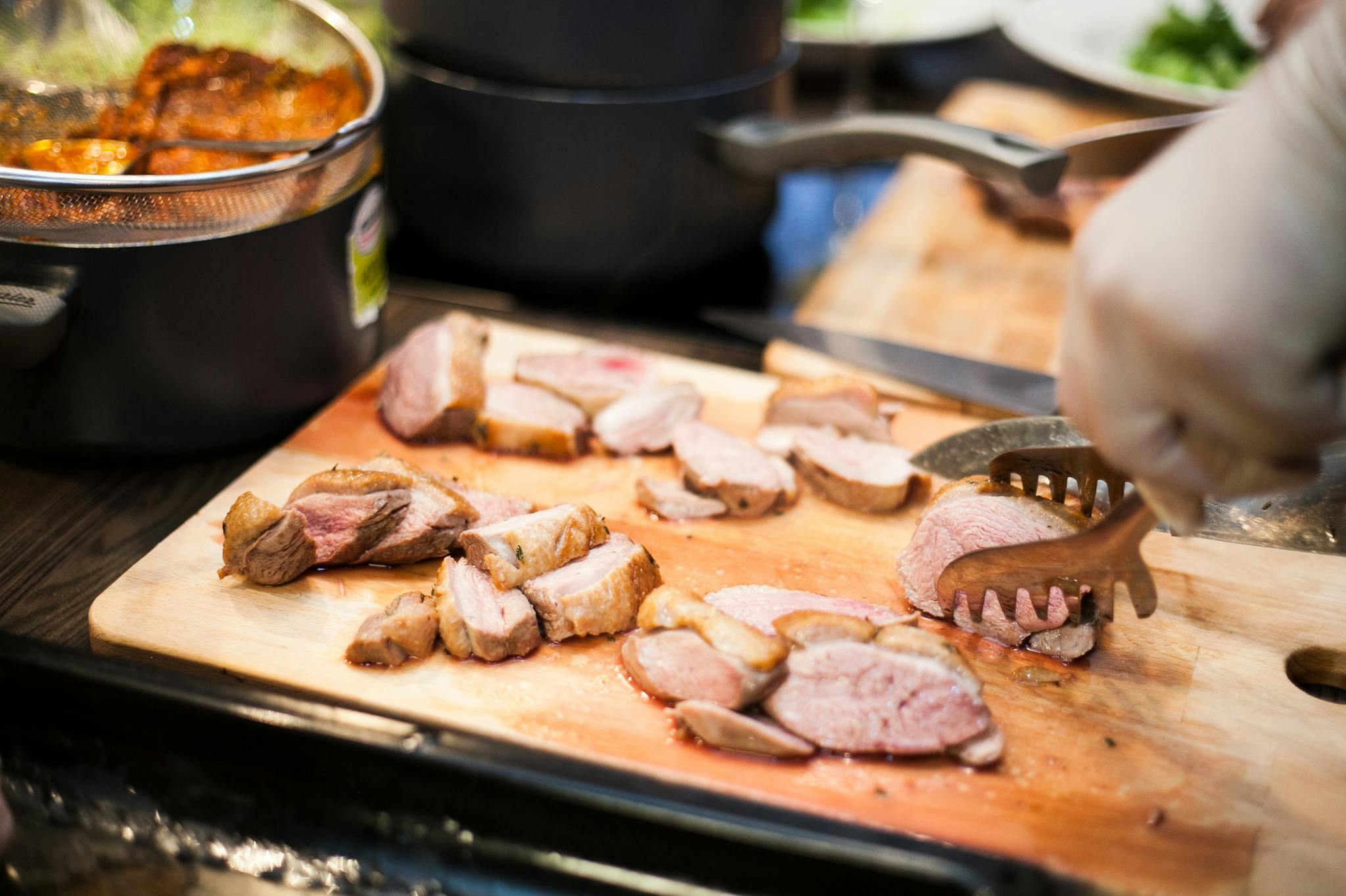 Close-up of cooked meat being sliced on a wooden board, highlighting food preparation.