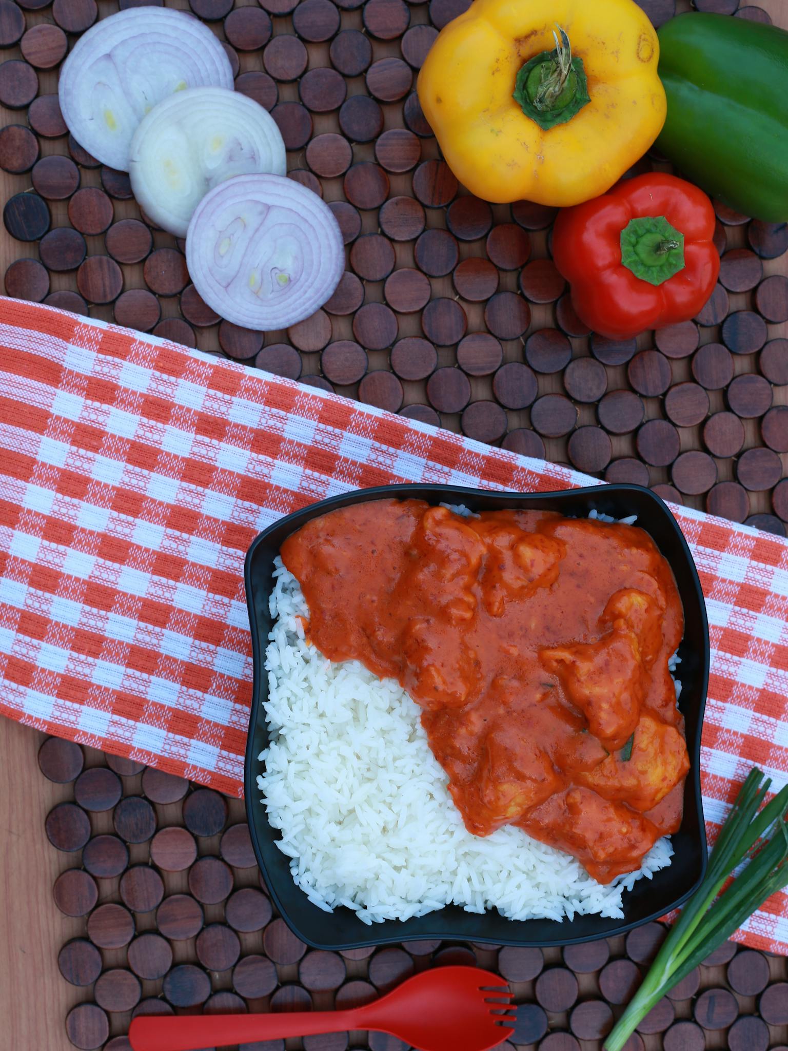 Delicious South Asian curry served with rice, surrounded by fresh vegetables and rustic elements.